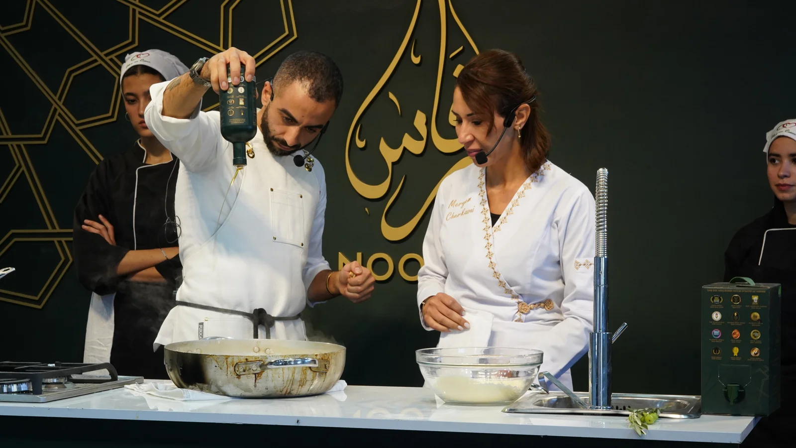 Chefs preparing a Moroccan recipe while adding premium olive oil during a live cooking workshop.