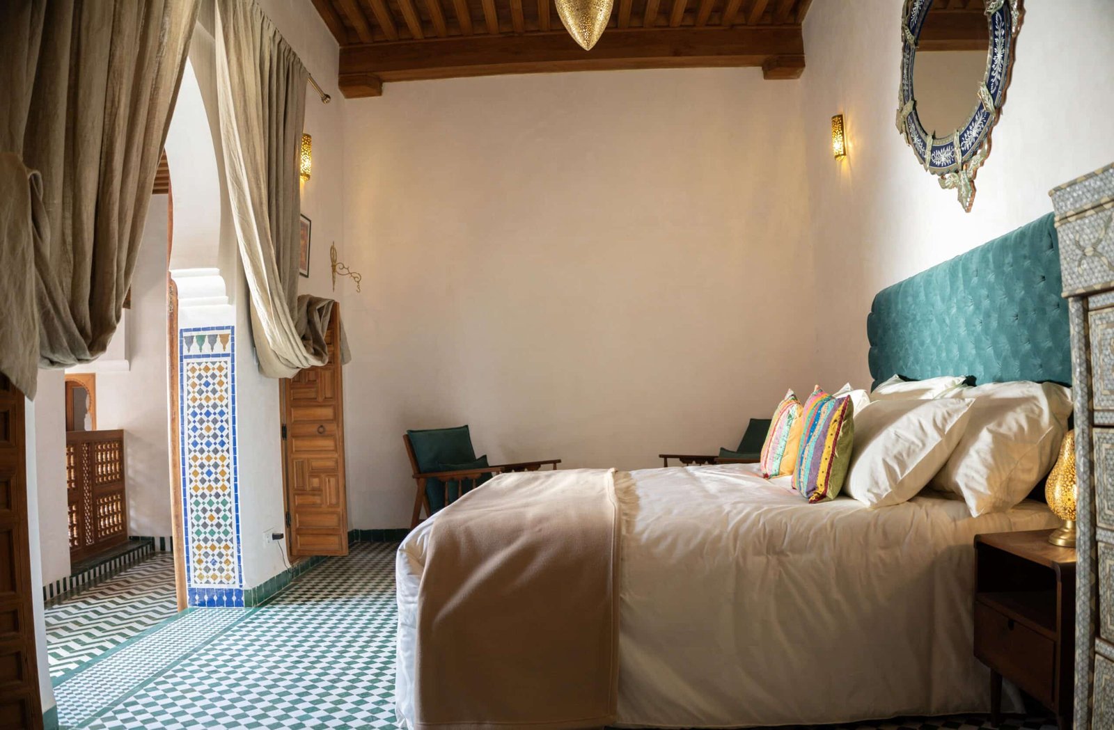 Deluxe room at Riad Dar Flores in Fes featuring a king-size bed, private seating area, traditional Moroccan architecture, and a view overlooking the riad courtyard.