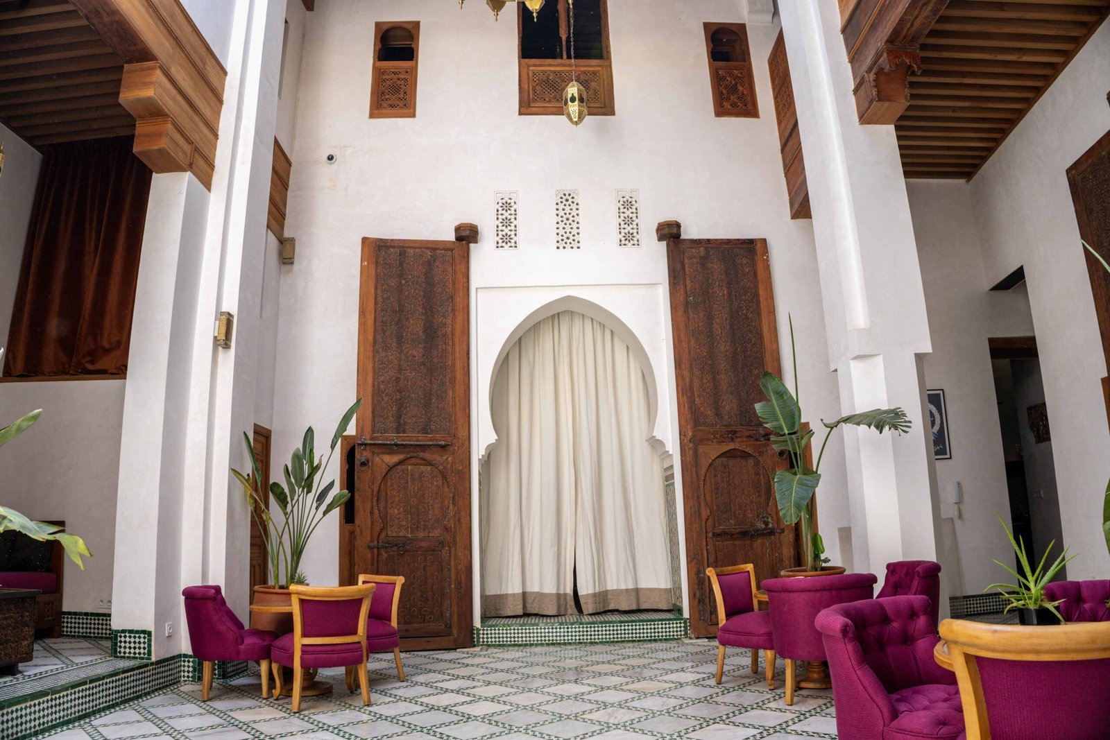 Luxury riad patio in Fes featuring traditional Moroccan architecture, handcrafted woodwork, and elegant lounge seating