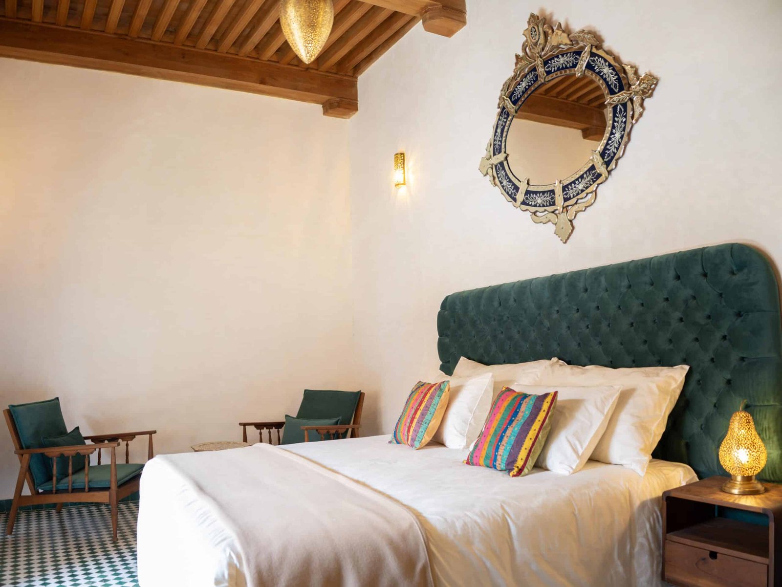 Luxury suite bedroom at Riad Dar Flores in Fes featuring a king-size bed, handcrafted cedar ceiling, colorful Moroccan décor, and boutique accommodation.