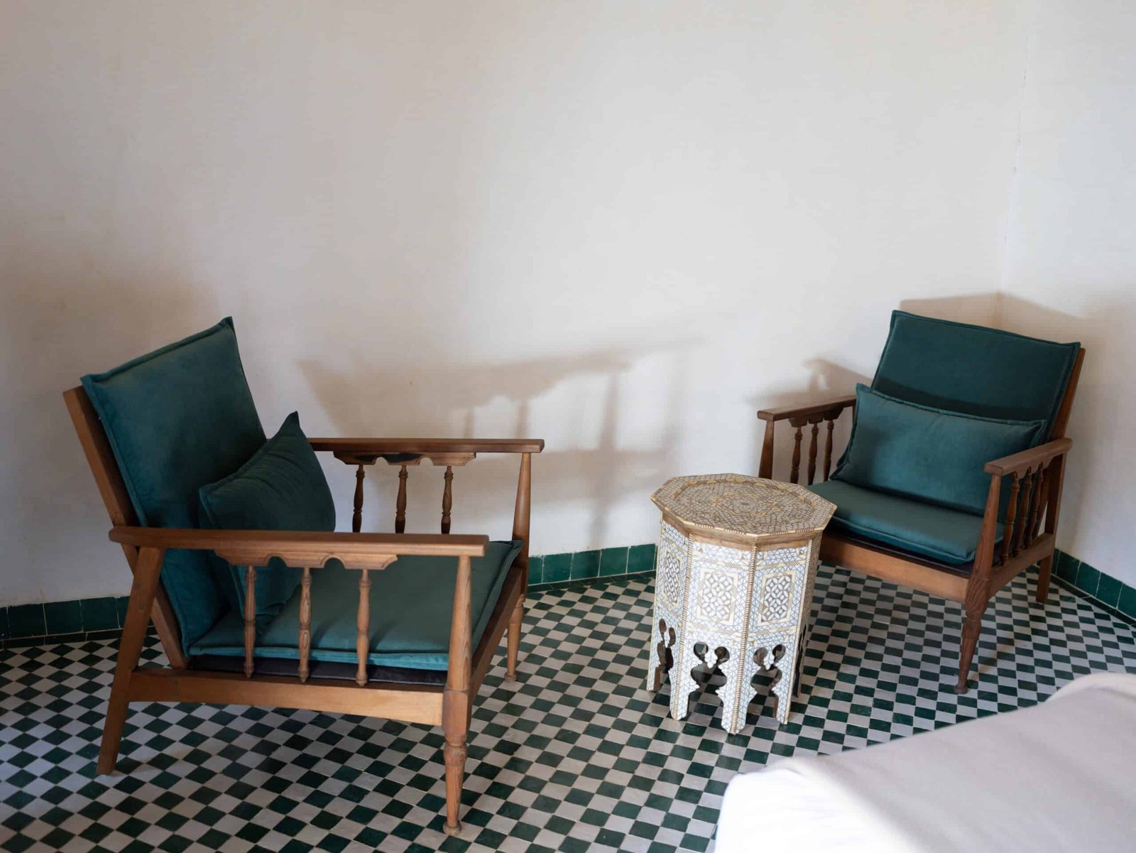 Cozy seating area inside a luxury suite at Riad Dar Flores in Fes with handcrafted Moroccan furniture and traditional zellige tile flooring.