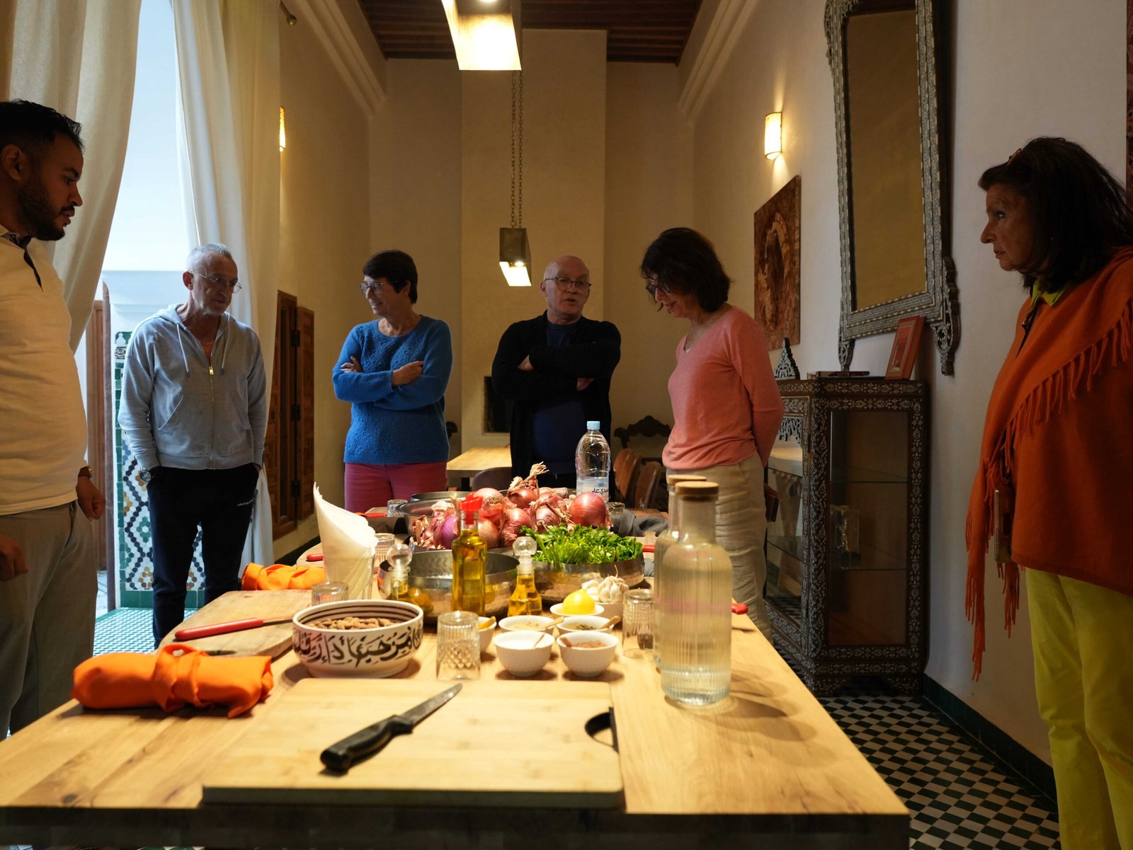 Cooking class participants gathered around a table of fresh ingredients in a Moroccan riad