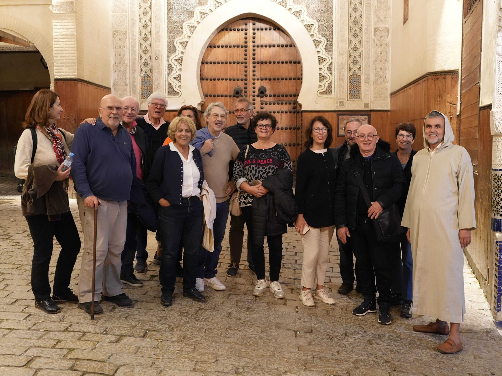 Group posing in a traditional Moroccan courtyard beside an arched wooden door