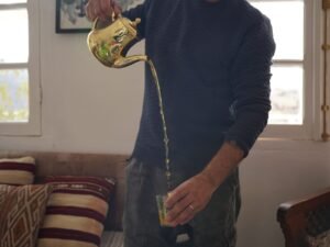 Traditional Moroccan mint tea being poured from a brass teapot into a glass.