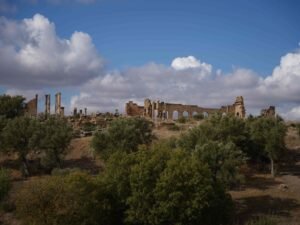 Panoramic view of the ancient Roman ruins of Volubilis in Morocco beneath dramatic clouds.